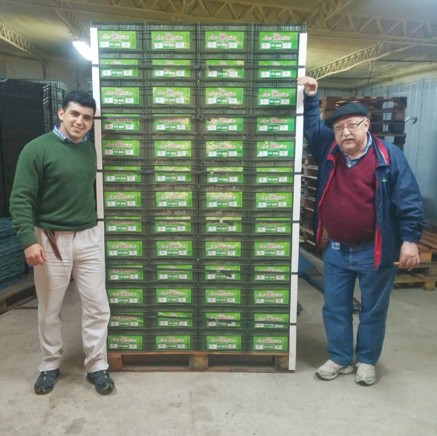 Alvaro junto a su abuelo frente a un pallet de cajones de fruta en el empaque